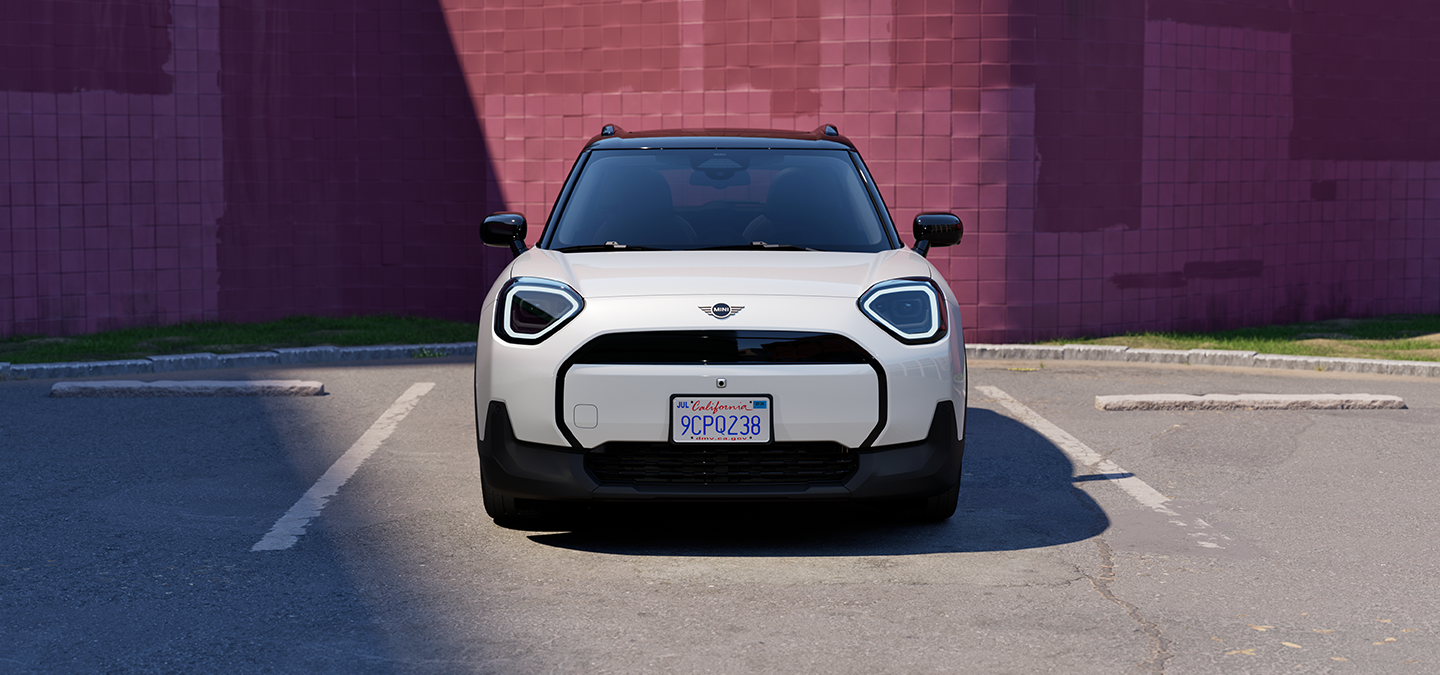 Täiselektriline Nanuq White’i värvitoonis ja musta katusega MINI Aceman parkimas, eestvaade.