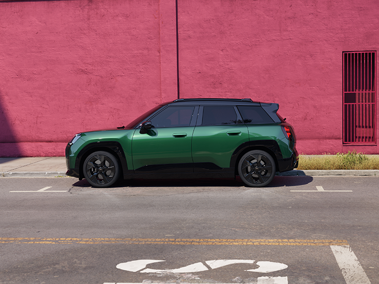 Täiselektriline British Racing Green värvitoonis ja musta katusega MINI Aceman tänaval, külgvaade.