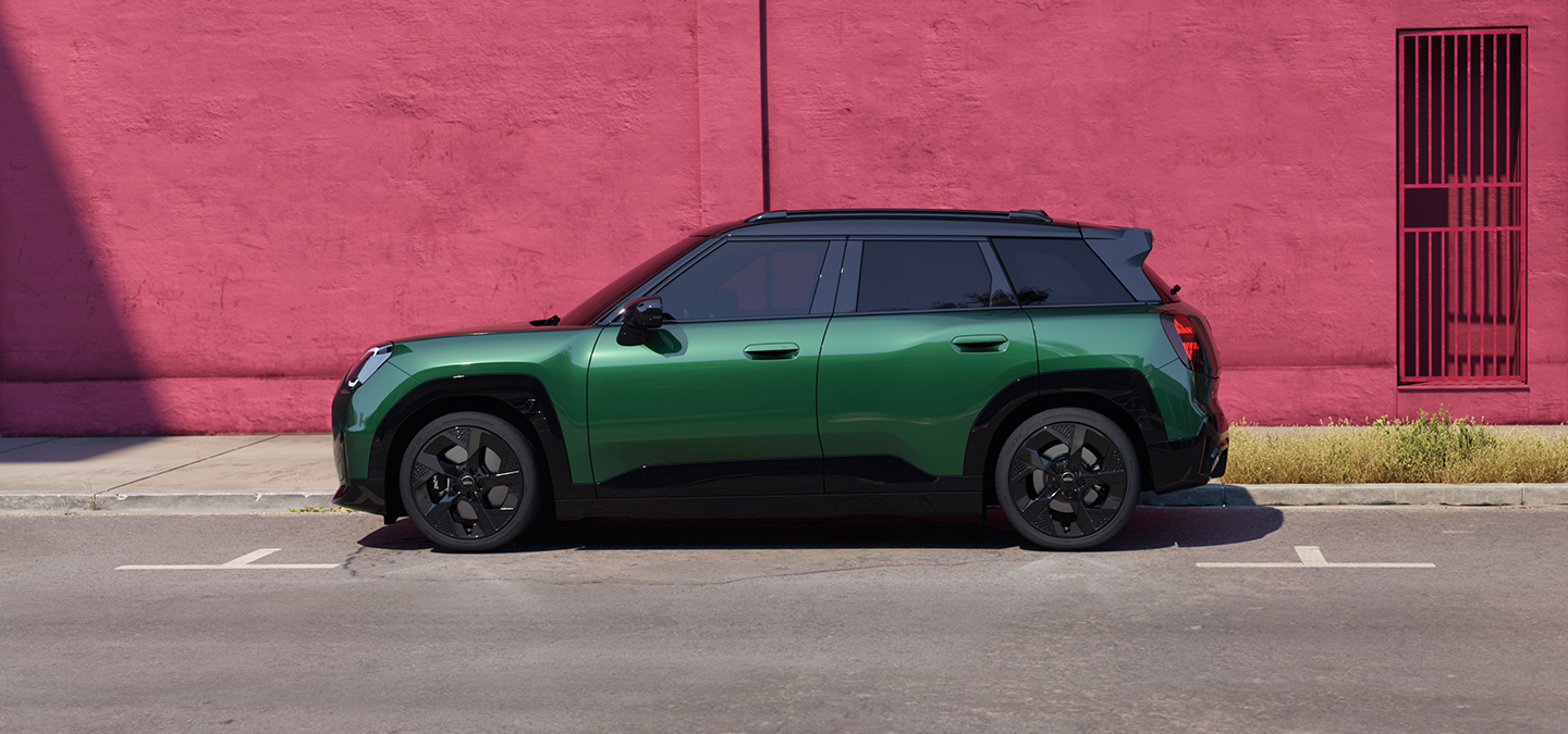 Täiselektriline British Racing Green värvitoonis ja musta katusega MINI Aceman tänaval, külgvaade.