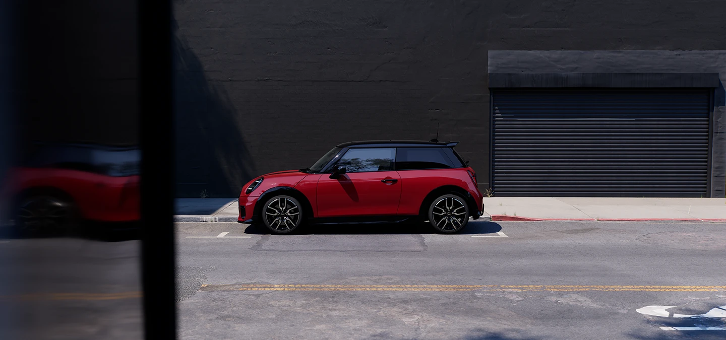 Chili Redi värvitoonis ja musta katusega MINI Cooper parkimas, külgvaade.
