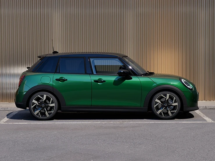 Viieukseline British Racing Greeni värvitoonis ja musta katusega MINI Cooper parkimas, külgvaade.