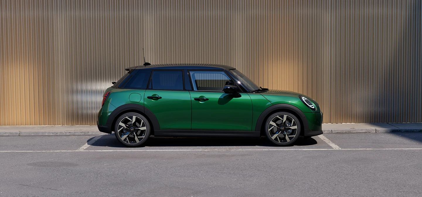 Viieukseline British Racing Greeni värvitoonis ja musta katusega MINI Cooper parkimas, külgvaade.