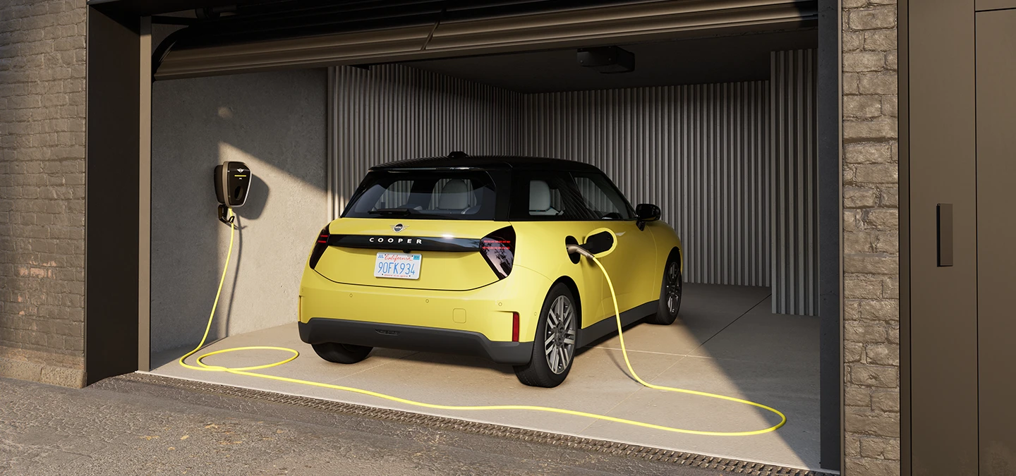 Täiselektriline Sunnyside Yellow värvitoonis MINI Cooper garaažis laadimas, tagantvaade.