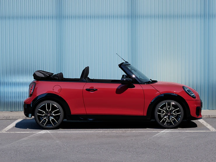 Külgvaade: tänaval seisev MINI Cooper Convertible värvitoonis Chili Red.