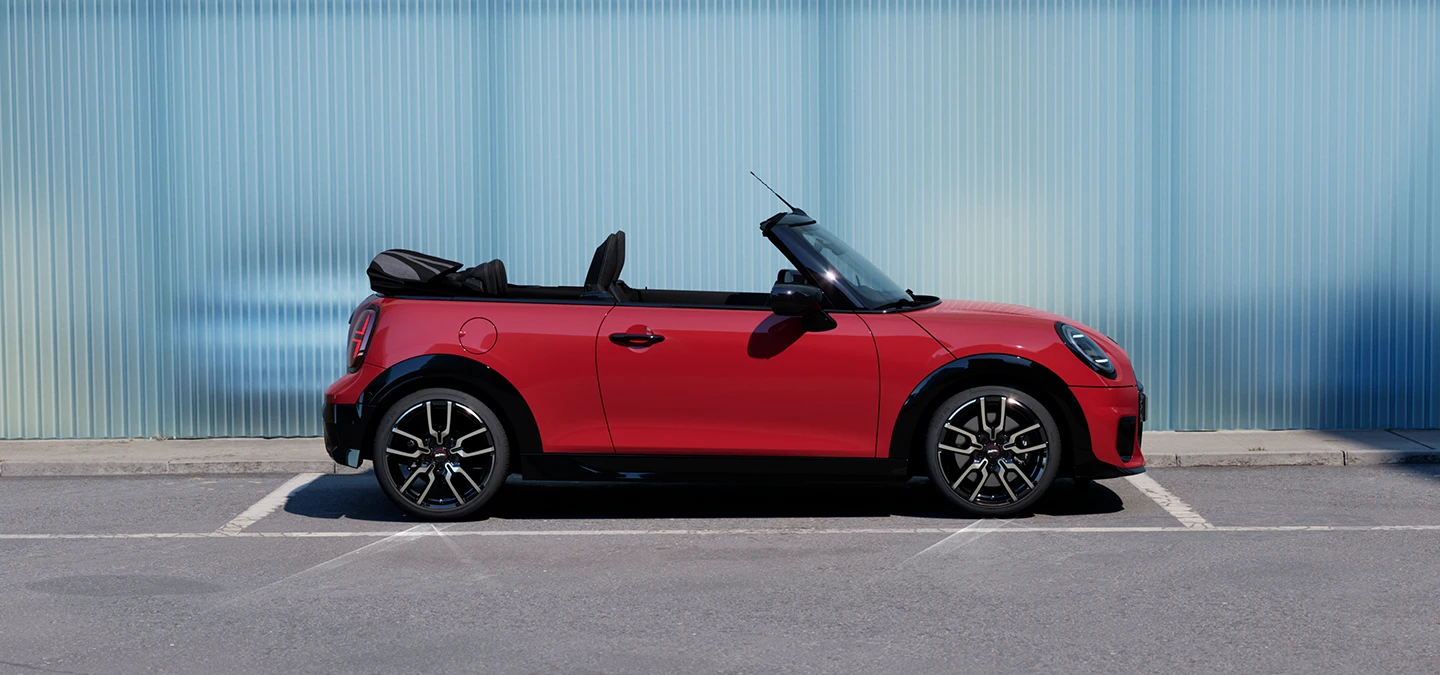 Külgvaade: tänaval seisev MINI Cooper Convertible värvitoonis Chili Red.