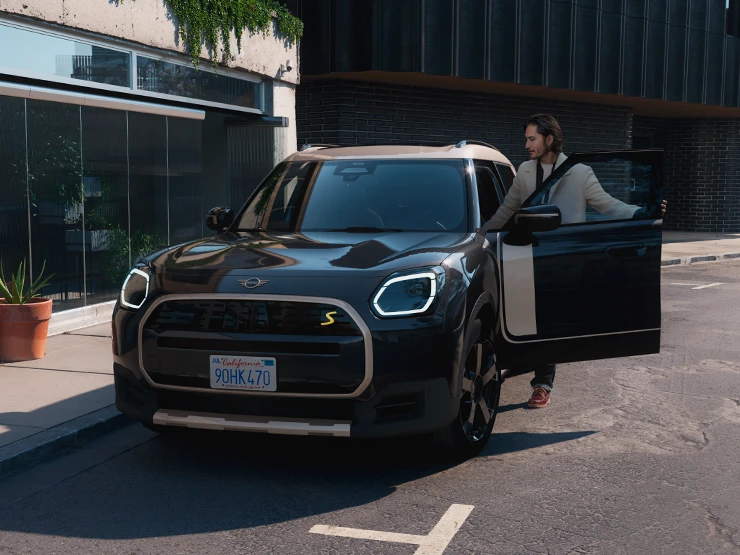 Midnight Blacki värvitoonis ja Vibrant Silveri katusega täiselektriline MINI Countryman tänaval, eestvaade.