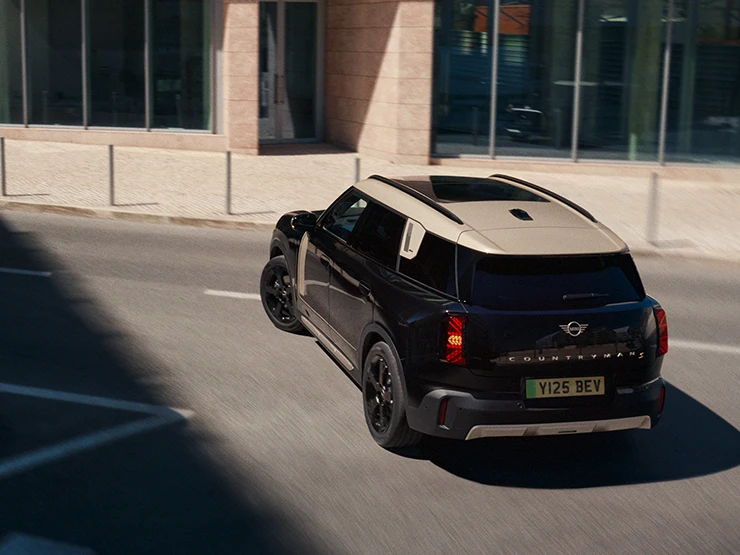 Midnight Blacki värvitoonis ja Vibrant Silveri katusega täiselektriline MINI Countryman parkimas, ülalt tagantvaade.