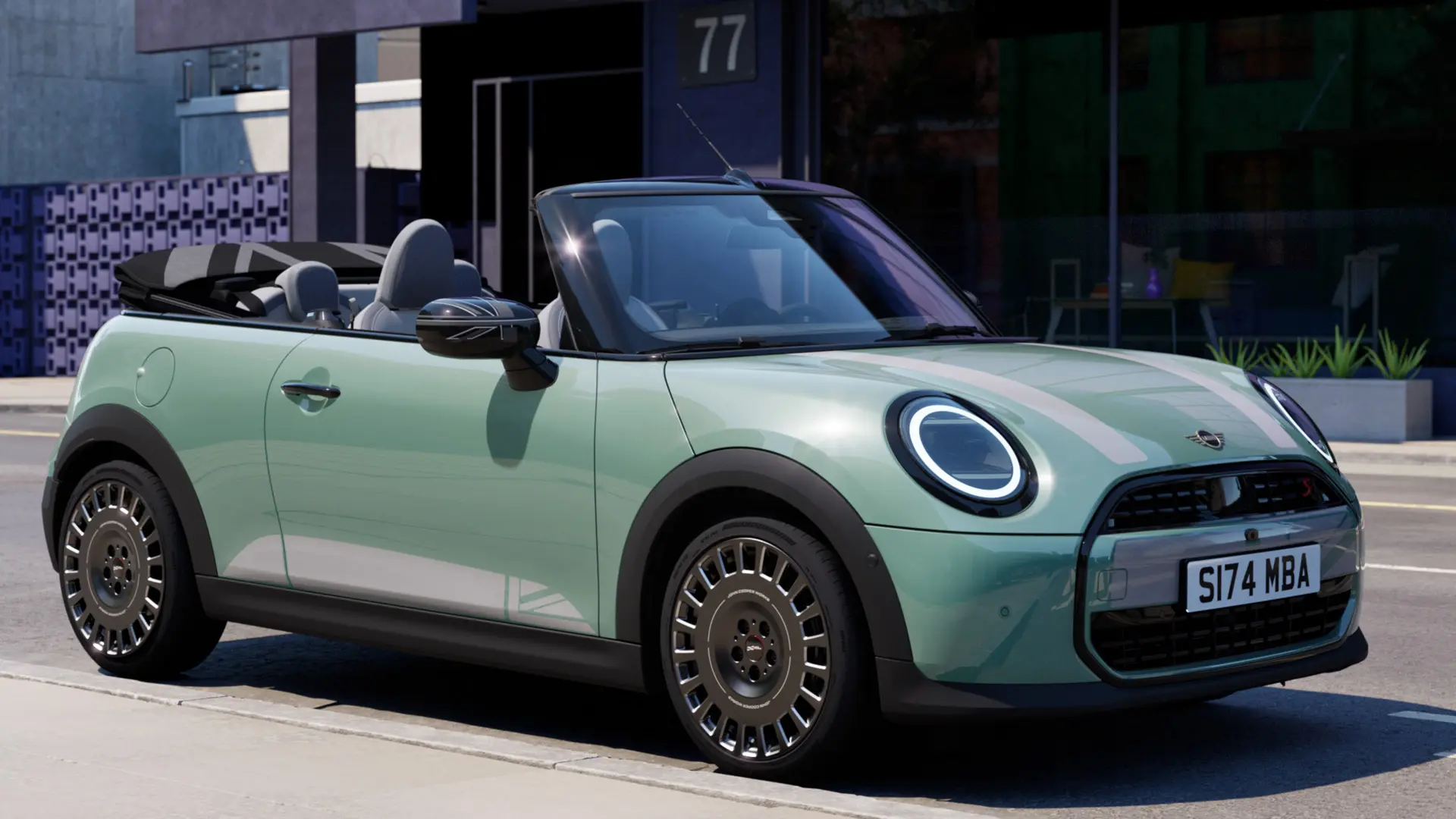 MINI Convertible eest külgvaates värvitoonis Ocean Wave Green, valgete MINI Heritage’i kapotikleebistega.