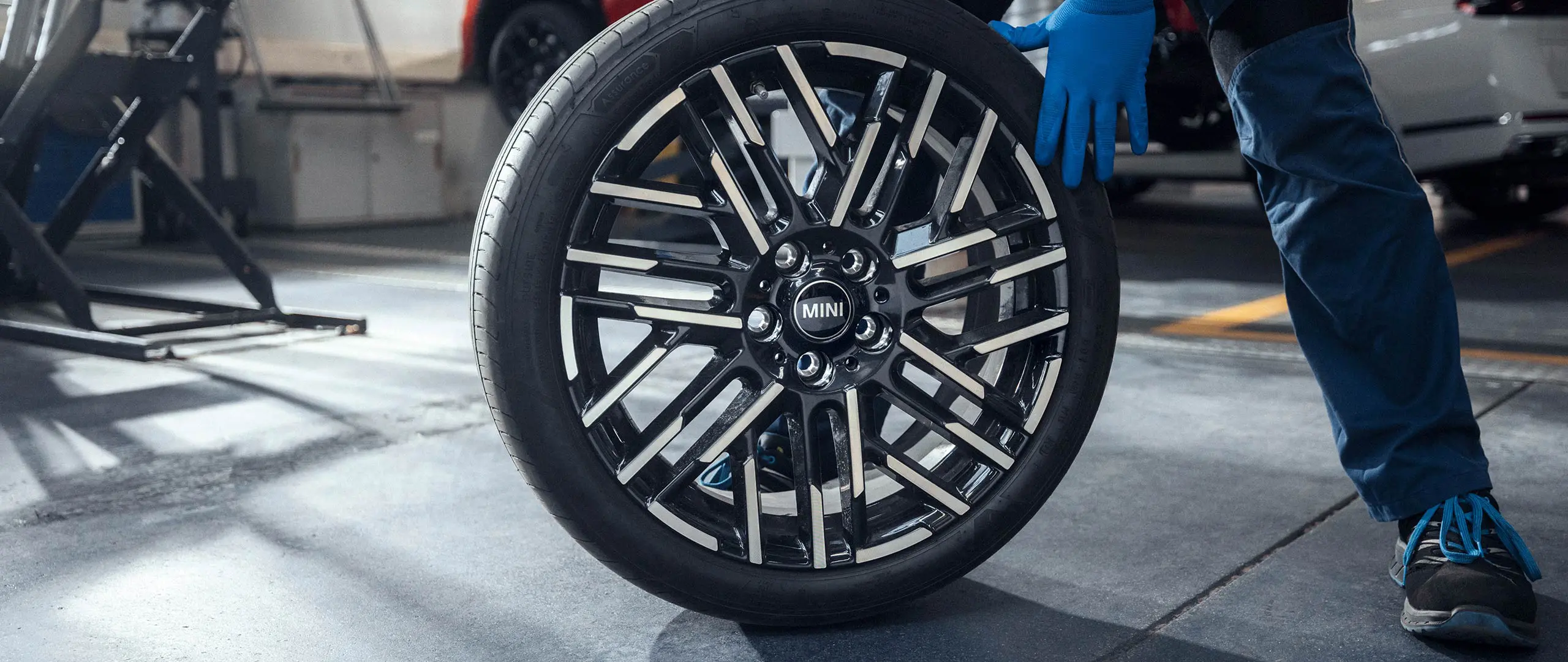 MINI partneri hooldustehnik veeretab 18-tollise kahevärvilise kergmetallvelje Night Flash Spoke paigale.